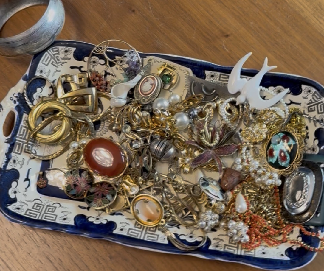 Antieke blauw-witte schaal vol vintage broches, ringen, camee's en kettingen