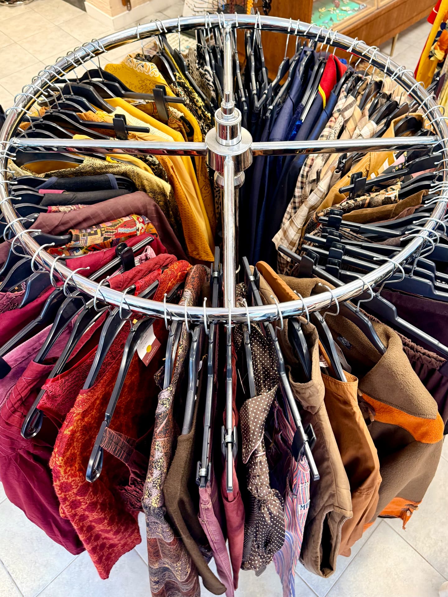 Rond draaiend rek vol vintage blouses, rokken en jassen in herfsttinten in de winkel