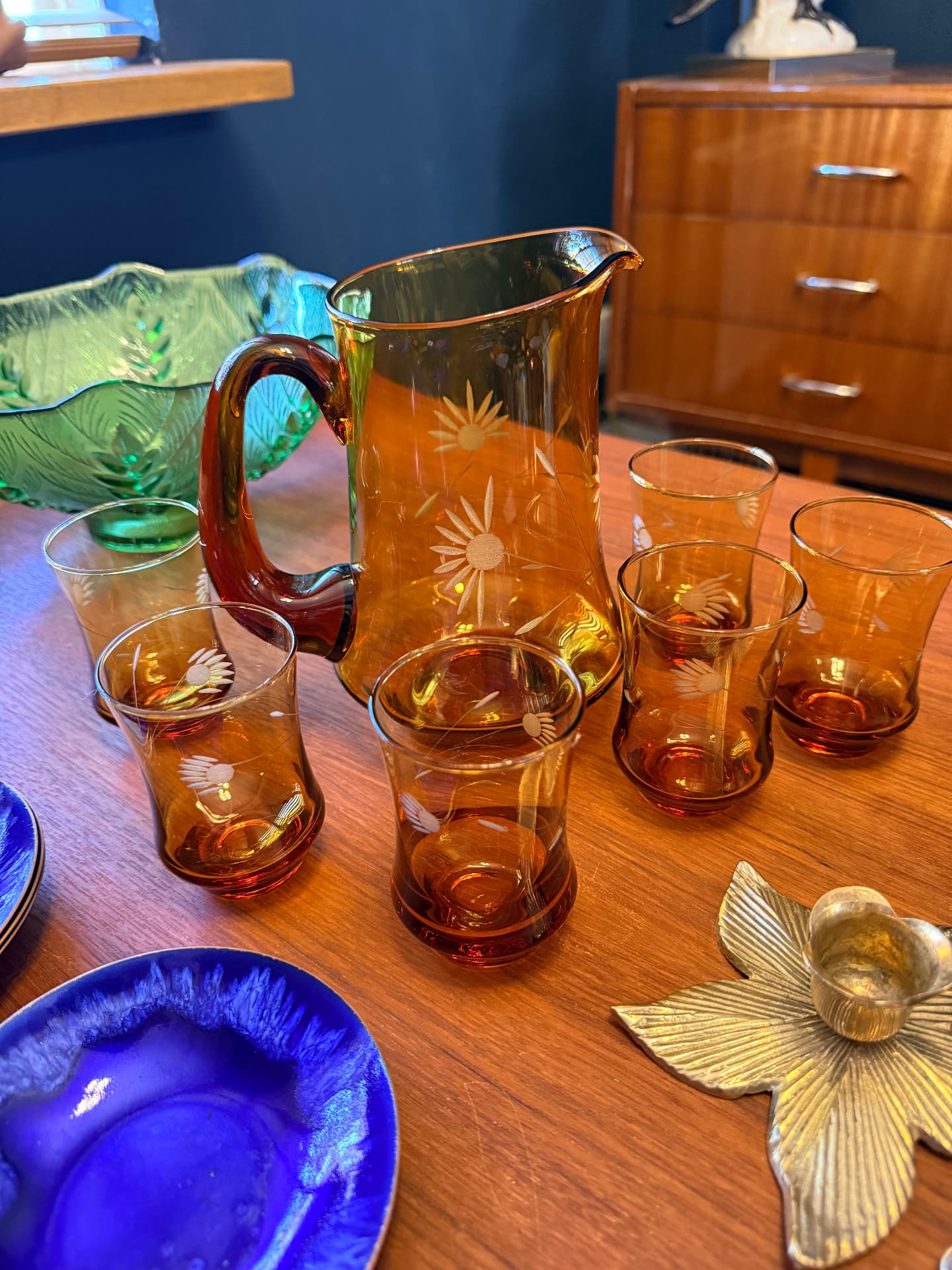 Vintage amberkleurige glazen kan met bijpassende glazen en gekleurd glaswerk op een teakhouten tafel